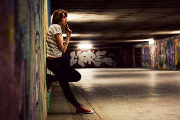 Stylish girl standing in grunge graffiti tunnel, shanty town