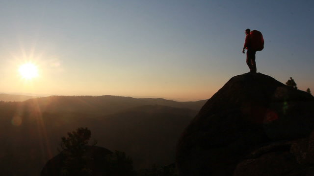 Hiker with backpack standing on top of a mountain
