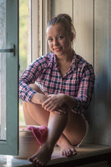 The girl sits on a window sill c with a bucket and a cloth