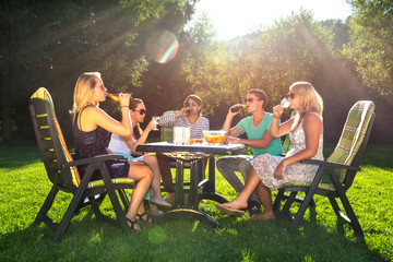Friends enjoying garden party on a sunny afternoon - obrazy, fototapety, plakaty