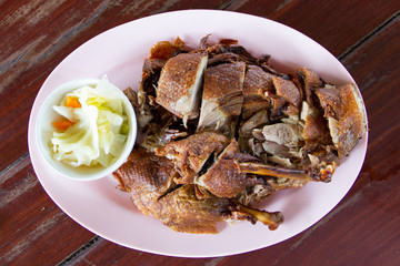 Duck fried in white dish on wooden table