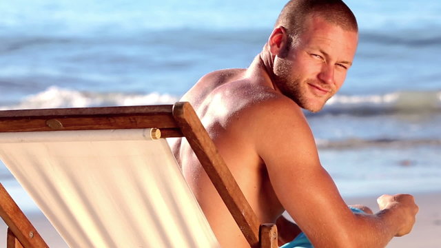 Handsome man with a straw hat relaxing on a deck chair