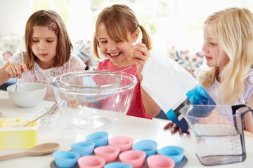 Obraz na płótnie Canvas Three Girls Making Cupcakes In Kitchen