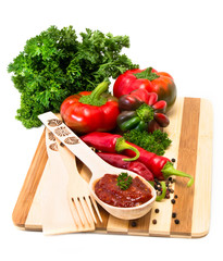 Mixture of peppers and sauce with them on a wooden plank.