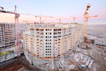 Lots of tower cranes build large residential building at evening