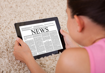 Young Woman Reading A News Article On Digital Tablet