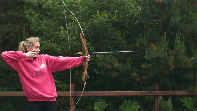 Blonde woman shooting bow and arrow