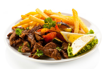 Grilled meat with French fries and vegetables