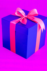 Obraz premium blue present box with red ribbon on pink background
