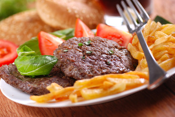 hamburger con contorno di patate fritte e pomodoro