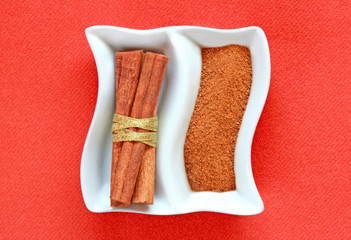 Cinamon sticks and cinamon powder on a plate.
