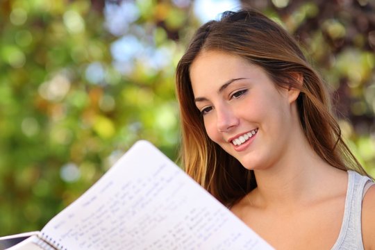 Beautiful teenager girl studying reading a notebook outdoor