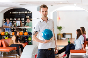 Confident Young Man With Bowling Ball in Club