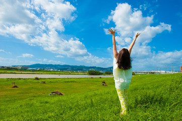 青空に向かって手を広げる一人の女性