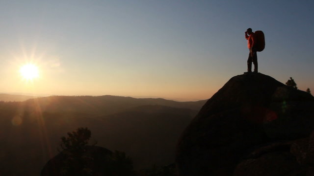Hiker with backpack standing on top of a mountain