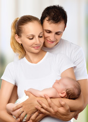 happy young family of mother, father and newborn baby in their a