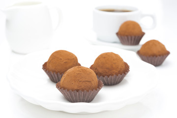Chocolate truffles on a plate and cup of coffee