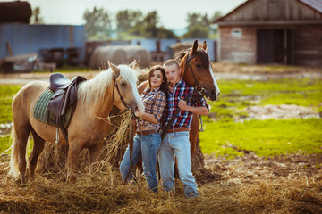couple standing on farm with horses