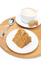 piece of honey cake and a cup of cappuccino on wooden board