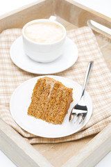 piece of honey cake and cup of cappuccino on a wooden tray