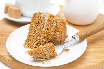 piece of honey cake on a plate and fork on wooden board