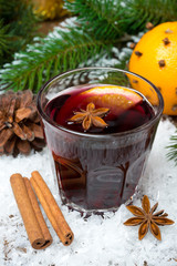 spicy mulled wine in the glass in the snow, vertical