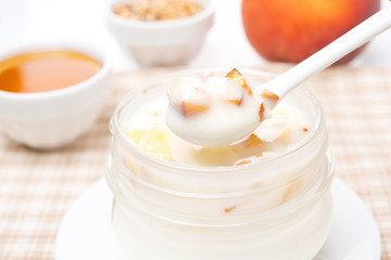 Obraz na płótnie Canvas yoghurt with honey, fresh peaches, nuts in a spoon