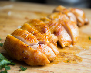 Sliced grilled chicken fillet on wooden board macro, clouse up