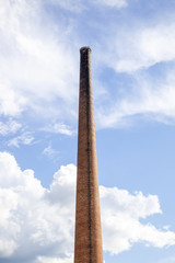 Old industrial brick chimney, against blue cloudy sky