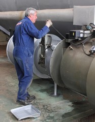 An engineer painting a large industrial steam boiler