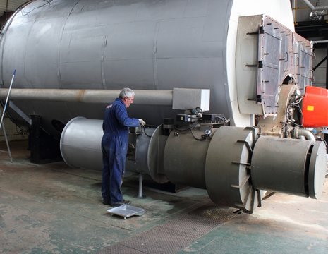 An engineer painting a large industrial steam boiler