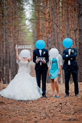 groom, bride and witnesses walking in autumn pine forest