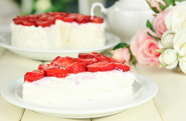 Cheesecake with fresh strawberry on white plate on wooden table