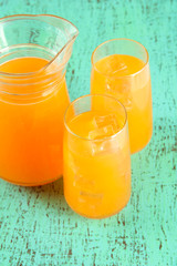 Glasses and pitcher of orange juice on blue wooden  background