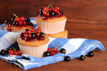 Tasty muffins with berries on wooden table