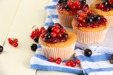 Tasty muffins with berries on white wooden table