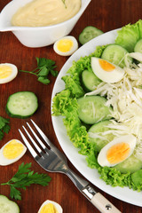Delicious salad with eggs, cabbage and cucumbers on wooden