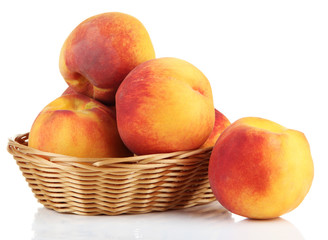 Ripe sweet peaches in wicker basket, isolated on white