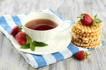 Cup of tea with cookies and strawberries on table close-up