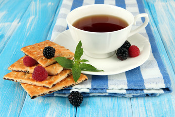 Cup of tea with cookies and berries on table close-up