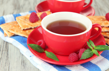 Cups of tea with cookies and raspberries on table close-up