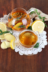 Kettle and cup of tea with ginger on napkin on wooden table