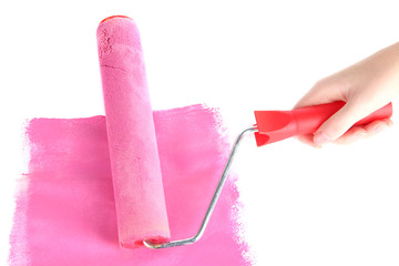Roller brush with pink paint in hand closeup