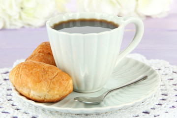 Tasty croissants and cup of coffee on table close-up