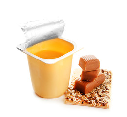 Tasty yogurt in open plastic cup, cookies and toffee candies