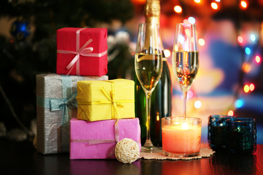 Glasses of champagne and gifts on bright background