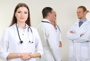 Fototapeta premium Doctor standing in front of coworkers on grey background