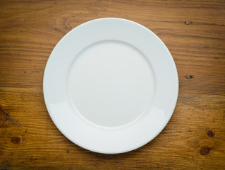 Empty white plate on wooden table