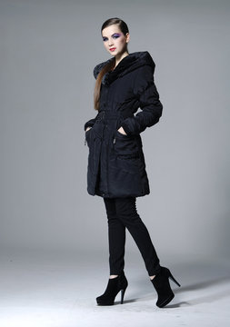 full length fashion model in black coat posing in studio