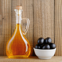 Bottle of olive oil and olives on old wooden background